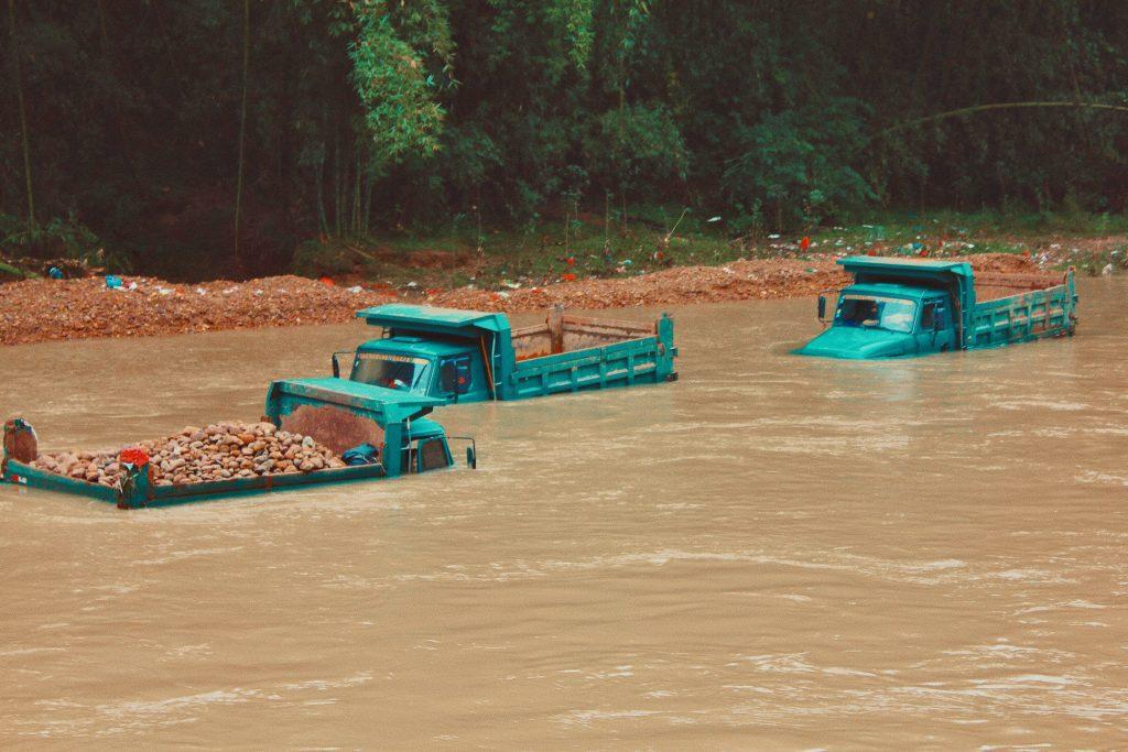 Three green trucks in a flooded area