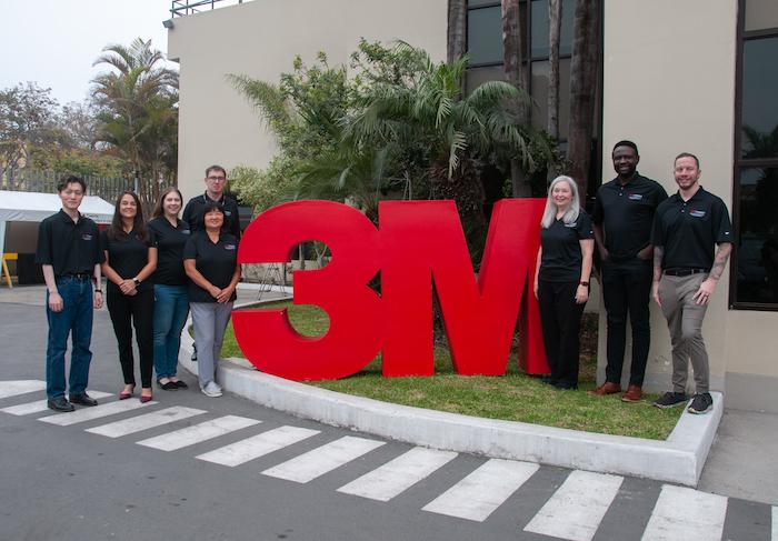 3M Volunteers standing in front of the 3M sign.