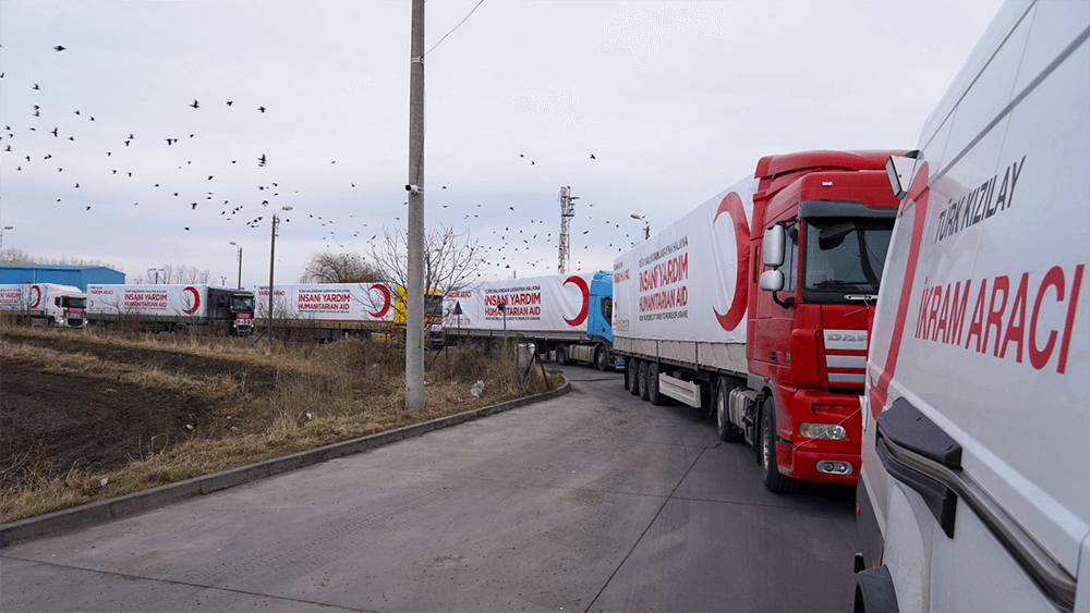 convoy of semi trucks all with red crescent logo on the side