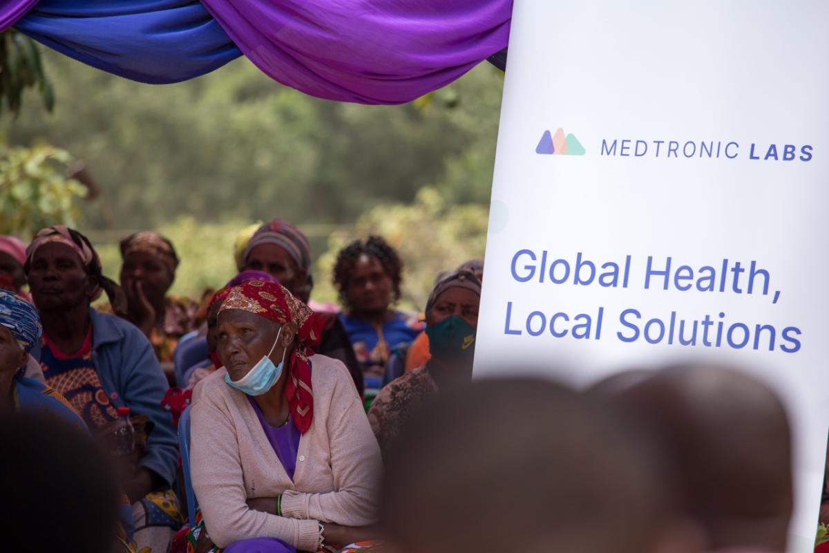 group of people sitting at presentation. A board reads, "Medtronic Labs: Global Health, Local Solutions"