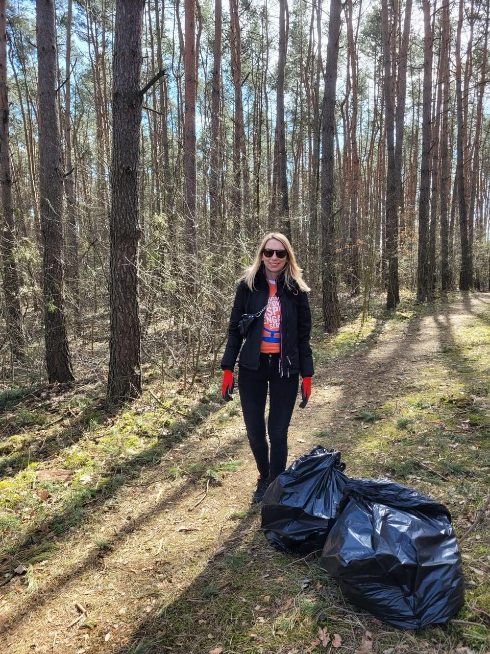 person standing near the woods with two large garbage bags