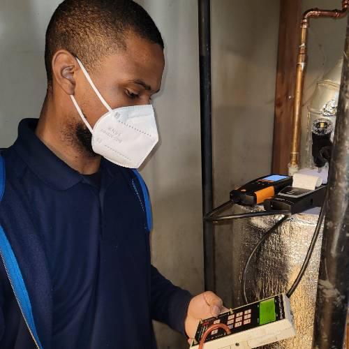 PSEG trainee, masked, is reading a gas meter during training.