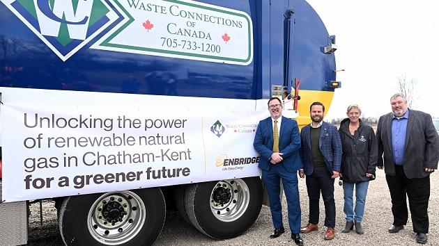 four people stand in front of a garbage truck with a poster "unlocking the power of renewable natural gas in Chatham-Kent for a greener future."