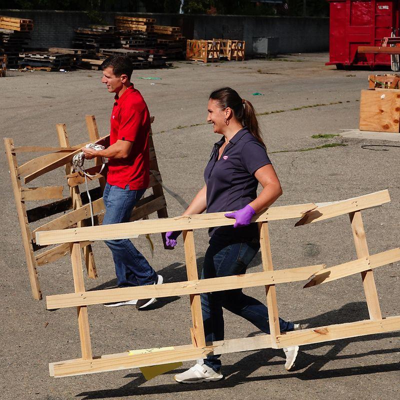 Two people carrying wooden pallets