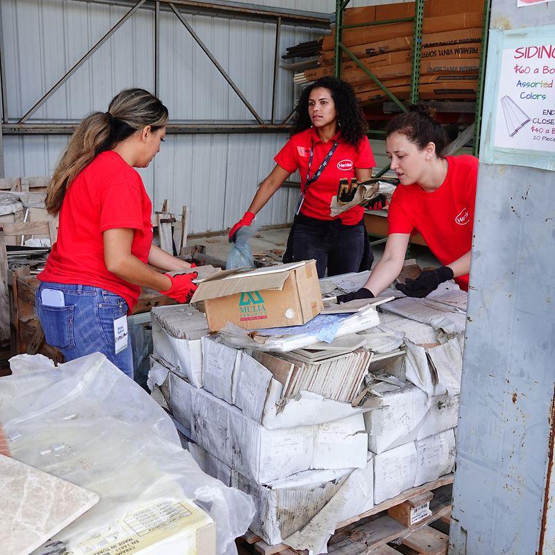 Volunteers sorting through pallets of tiles in a storage warehouse