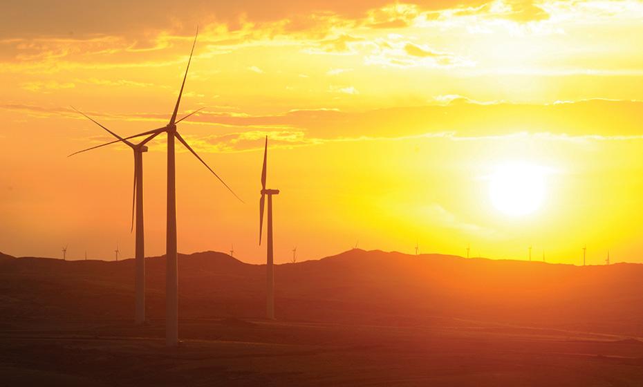three wind turbines with a setting sun in the background