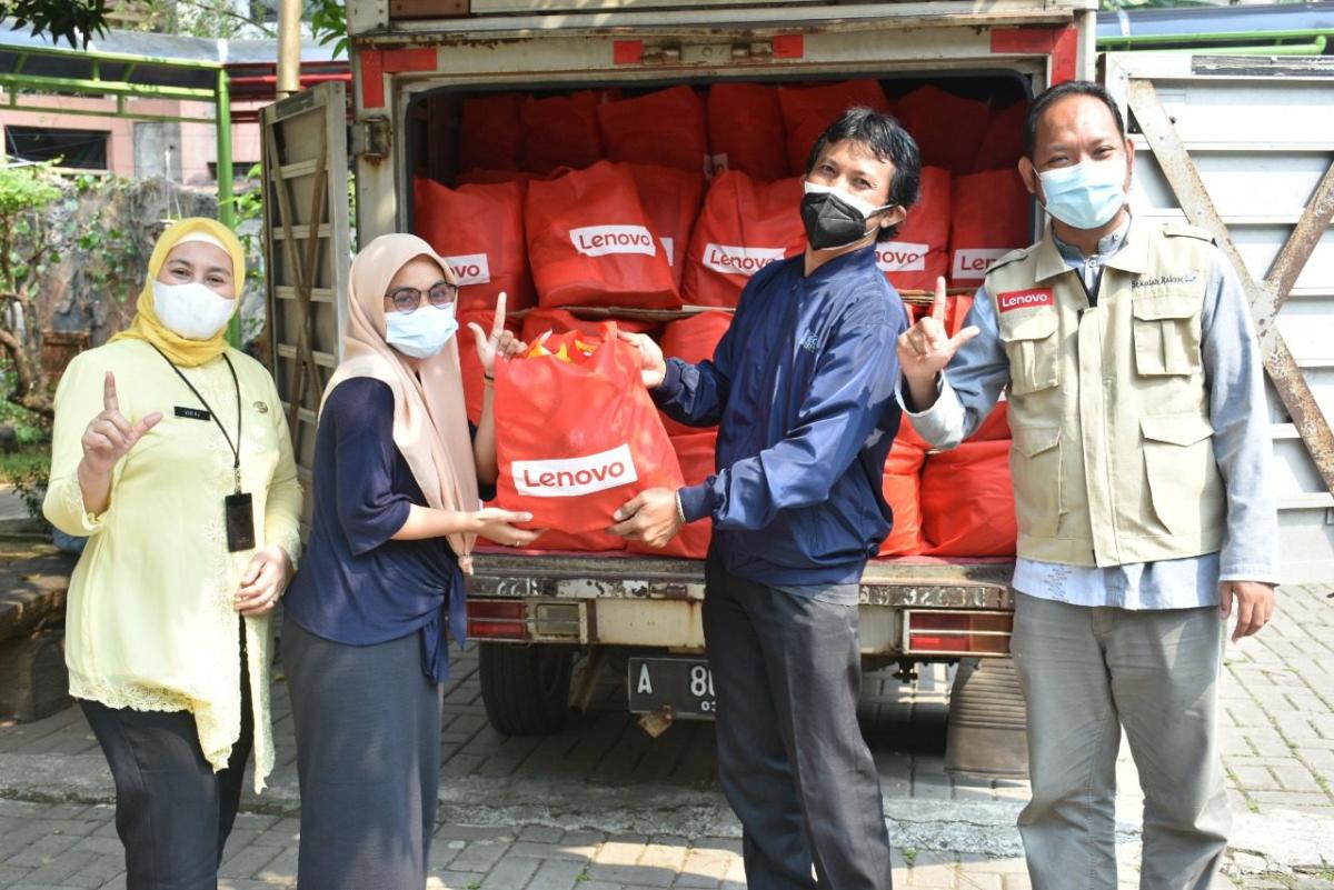 4 people standing in front of a truck filled with Red Lenovo bags
