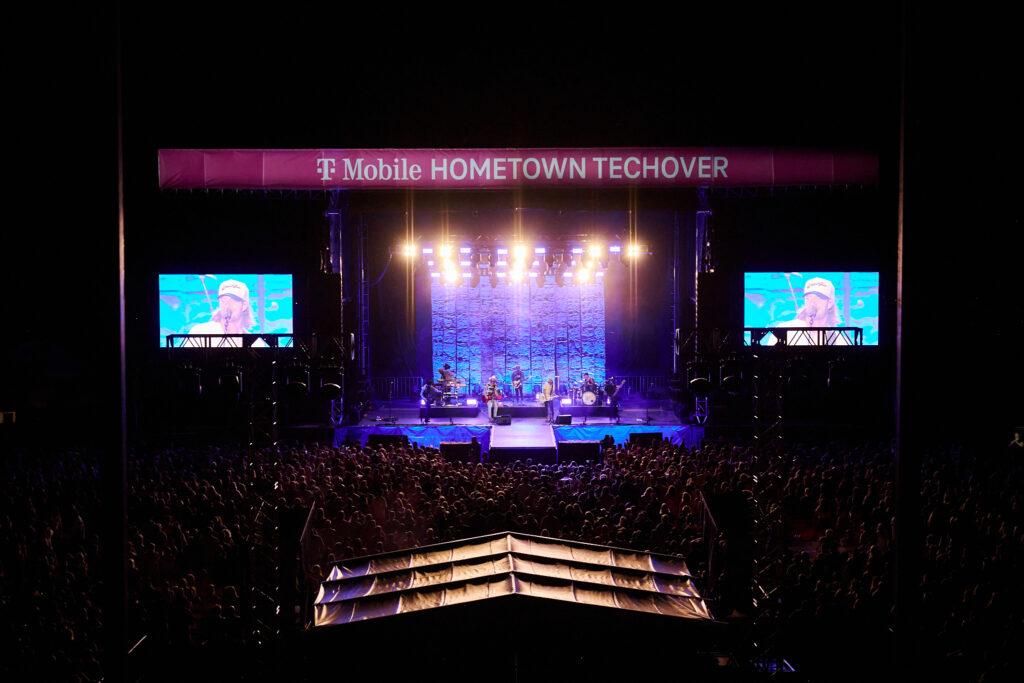 aerial view of a lit up concert stage, two monitors on the sides