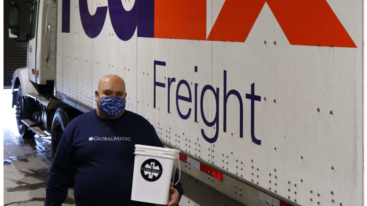 man wearing GlobalMedic shirt stands next to FedEx freight truck