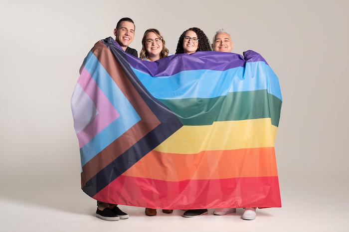 Ben C., Kat J., Jess G., & Michael G.   GoDaddy GDUnited, holding up a Pride flag.