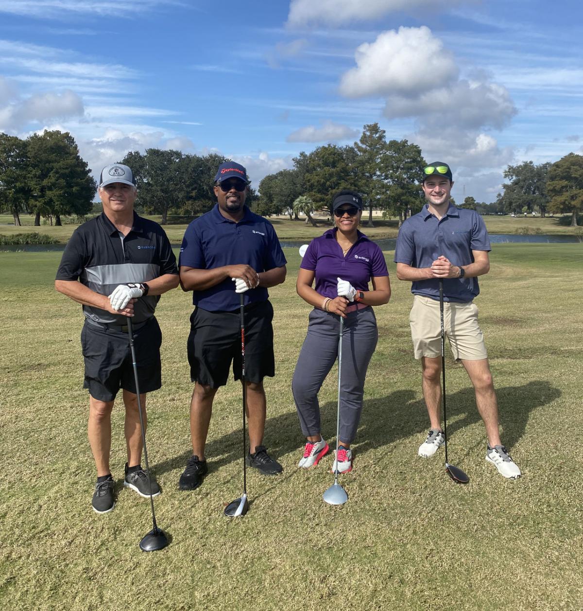 Four people holding golf clubs on a course
