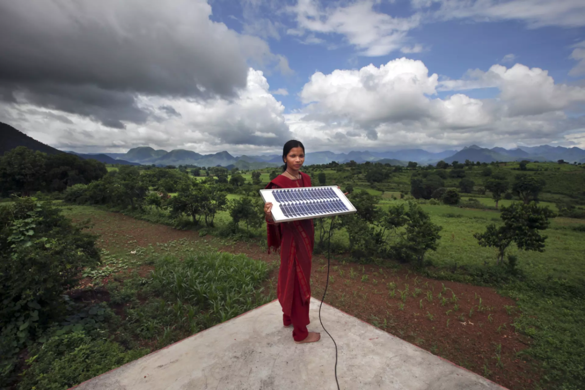 person holding solar panel with beautiful landscape behind
