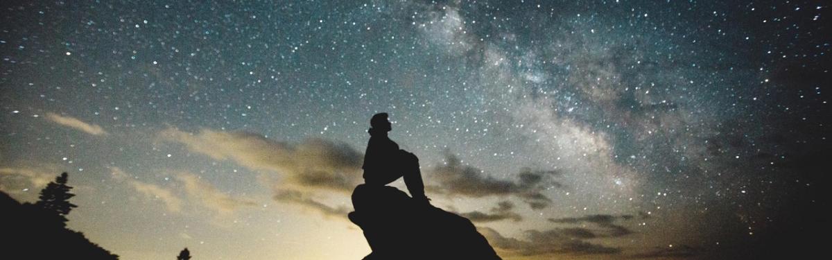 Person sitting on rock with the night sky background