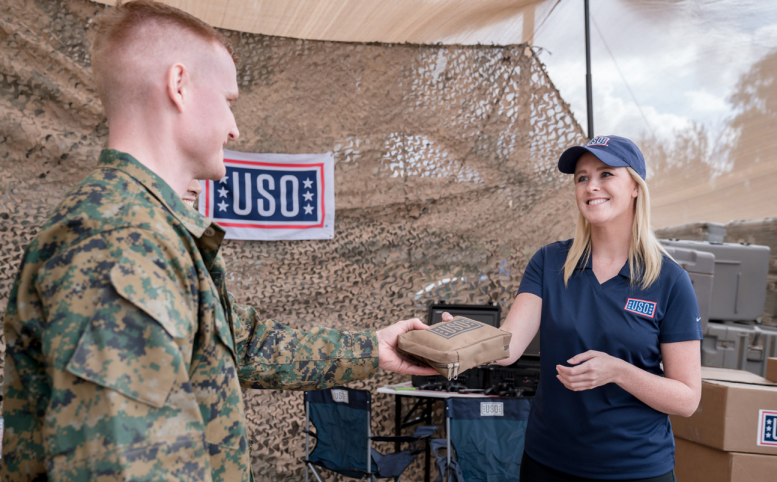 Woman from USO handing something to a soldier
