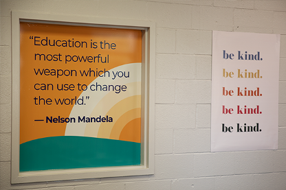 two signs reading: "education is the most powerful weapon which you can use to change the world" and "be kind"
