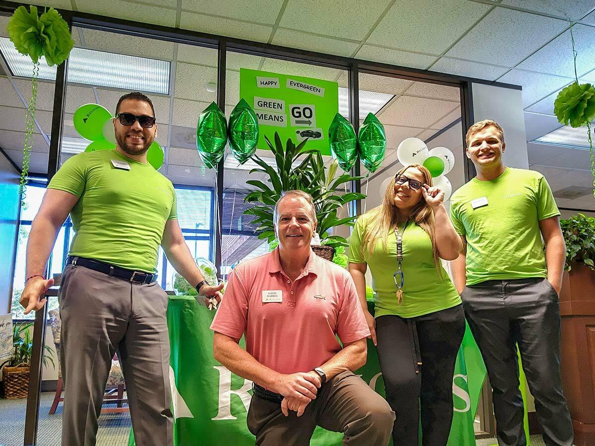 Employees in Green shirts in front of a poster that says "Green means GO"