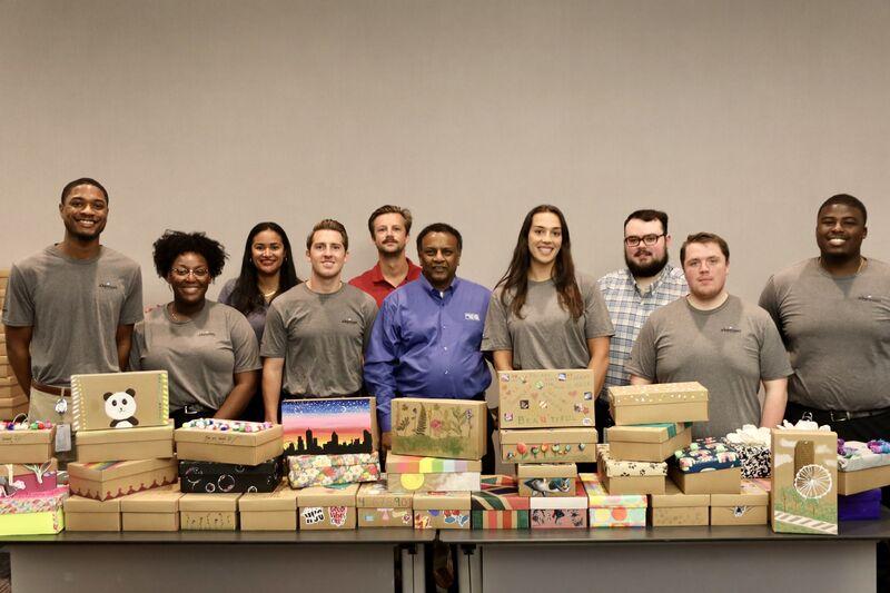 group of people behind a table of stacked shoe boxes